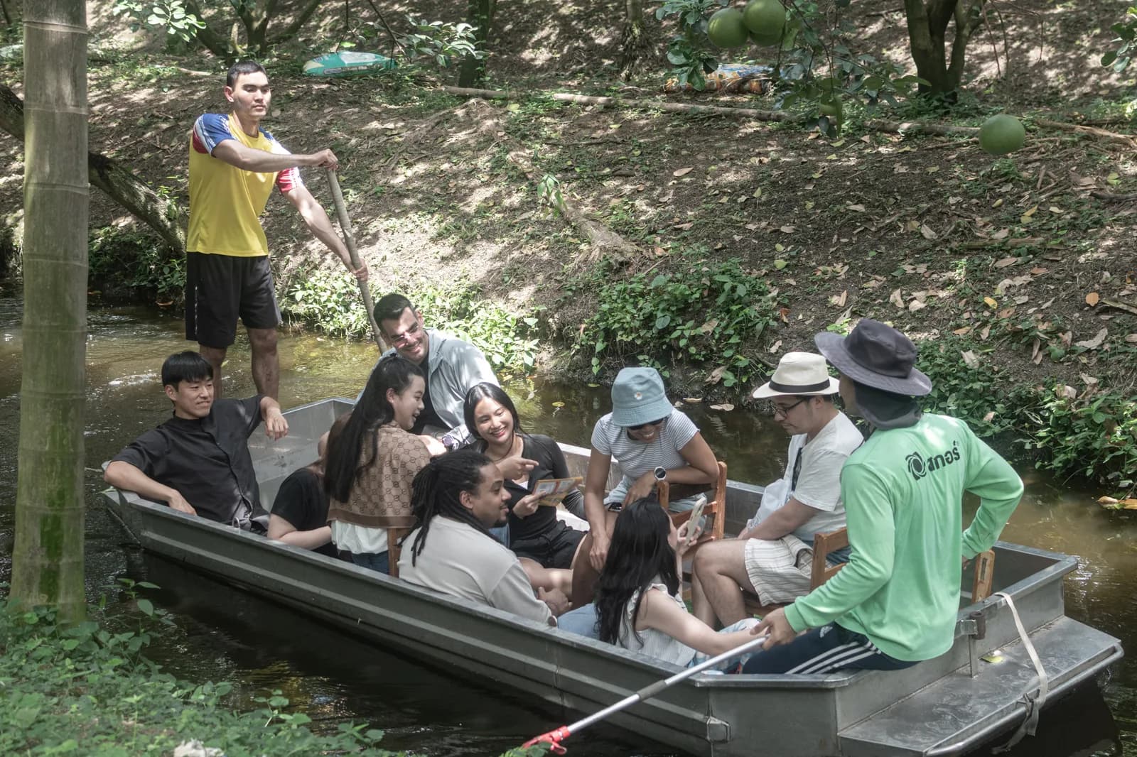 A small O-World Travel group sharing a longtail boat through a shaded pomelo orchard canal
